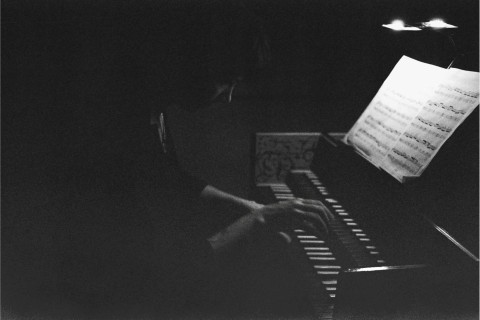 Close-up photo of Medea Bindewald playing the harpsichord in subdued lighting.