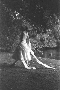 Photo of Louise Hughes wearing a dress that captures the spirit of a swan as she walks along a river bank