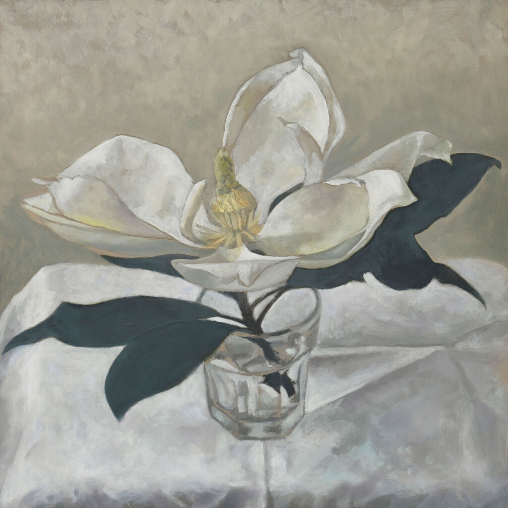 Bold white petals with soft yellow center with almost black leaves, with dark stalk into a french style tumbler of water. Soft grey/ putty coloured marked background. Tab;e cloth has purply shadows and shows the folds and creases in the cloth and the edge of the table by the shading of the cloth.