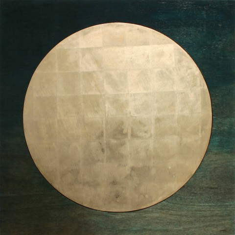 Photo showing gold metallic disc on a square wood block stained with green paint