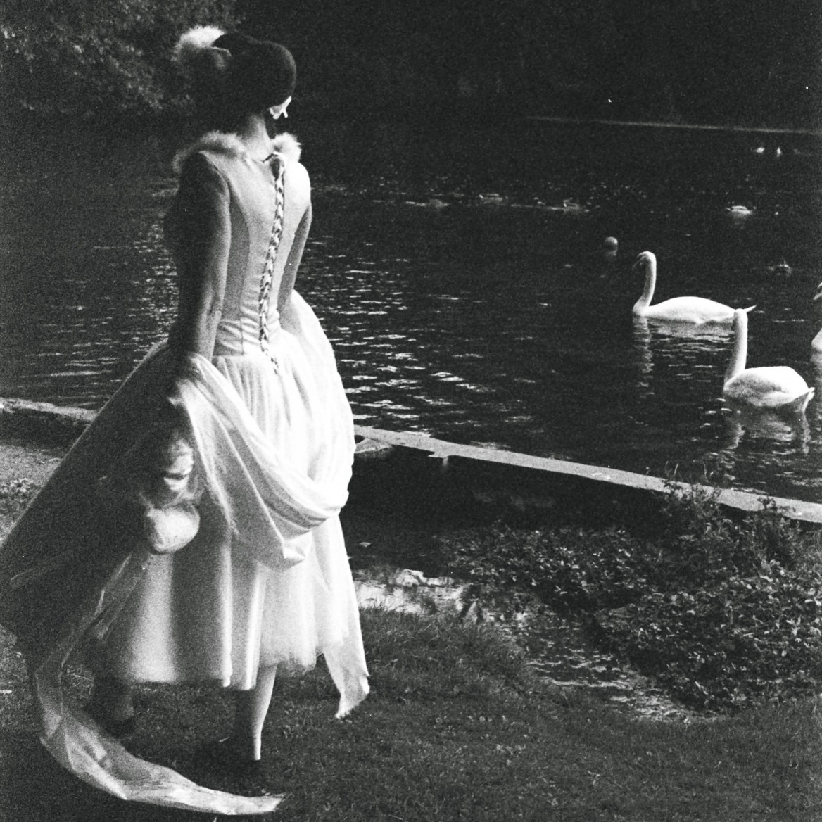 Film still shows Louise Hughes performing as the swan as she walks along the Kearsney Abbey riverbank next to real-life swans