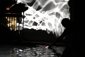 Kate makes additional waves and ripples in the water to produce new patterns in the projection