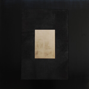 Facing view of the artwork "Trinity", which has a small oblong gold shape in the middle, surrounded by a burnt black wood rectangle, which is surrounded by a black lacquer larger rectangle.